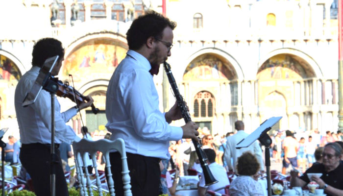 Man in white shirt and black pants playing clarinet alongside a band on stage