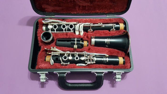Disassembled clarinet in case with red lining on violet background
