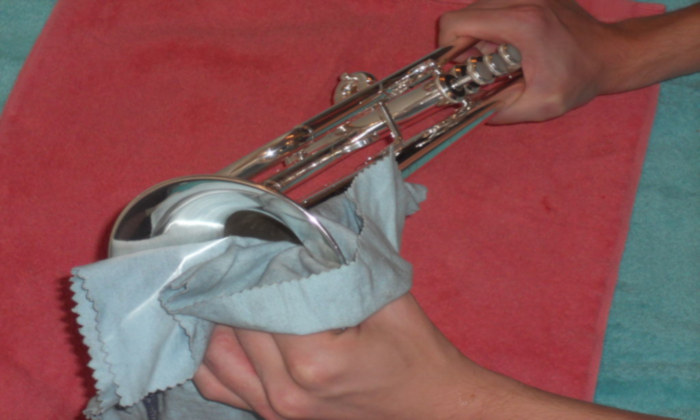 Polishing a silver trumpet with a microfiber cloth