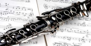 A clarinet resting on top an open book of sheet music