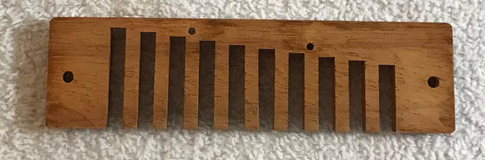 Wooden comb from a Blues Harp harmonica resting on a white towel