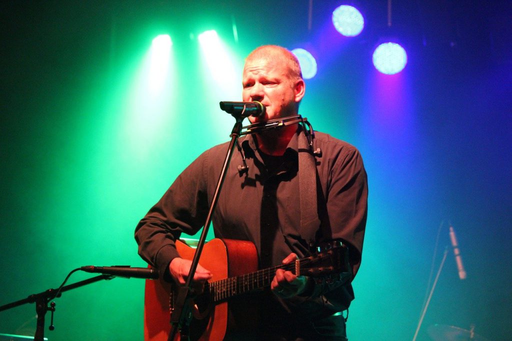 Man playing harmonica and acoustic guitar on stage