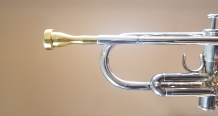 Brass trumpet mouthpiece inserted into a silver-colored trumpet