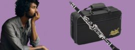 Dark-skinned man staring distantly at a Jean Paul USA CL-300 student clarinet with case on purple background